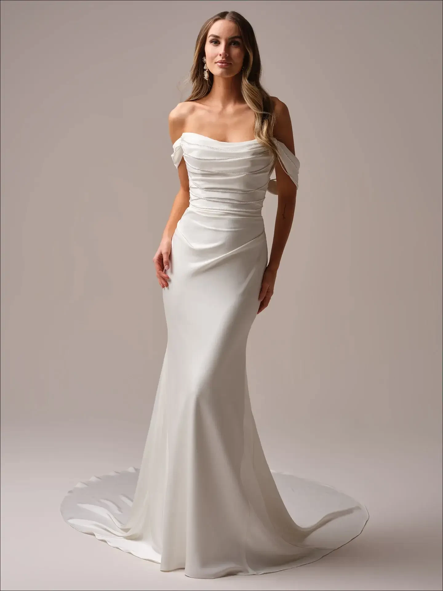 model is wearing a romantic off the shoulder fit and flare wedding dress