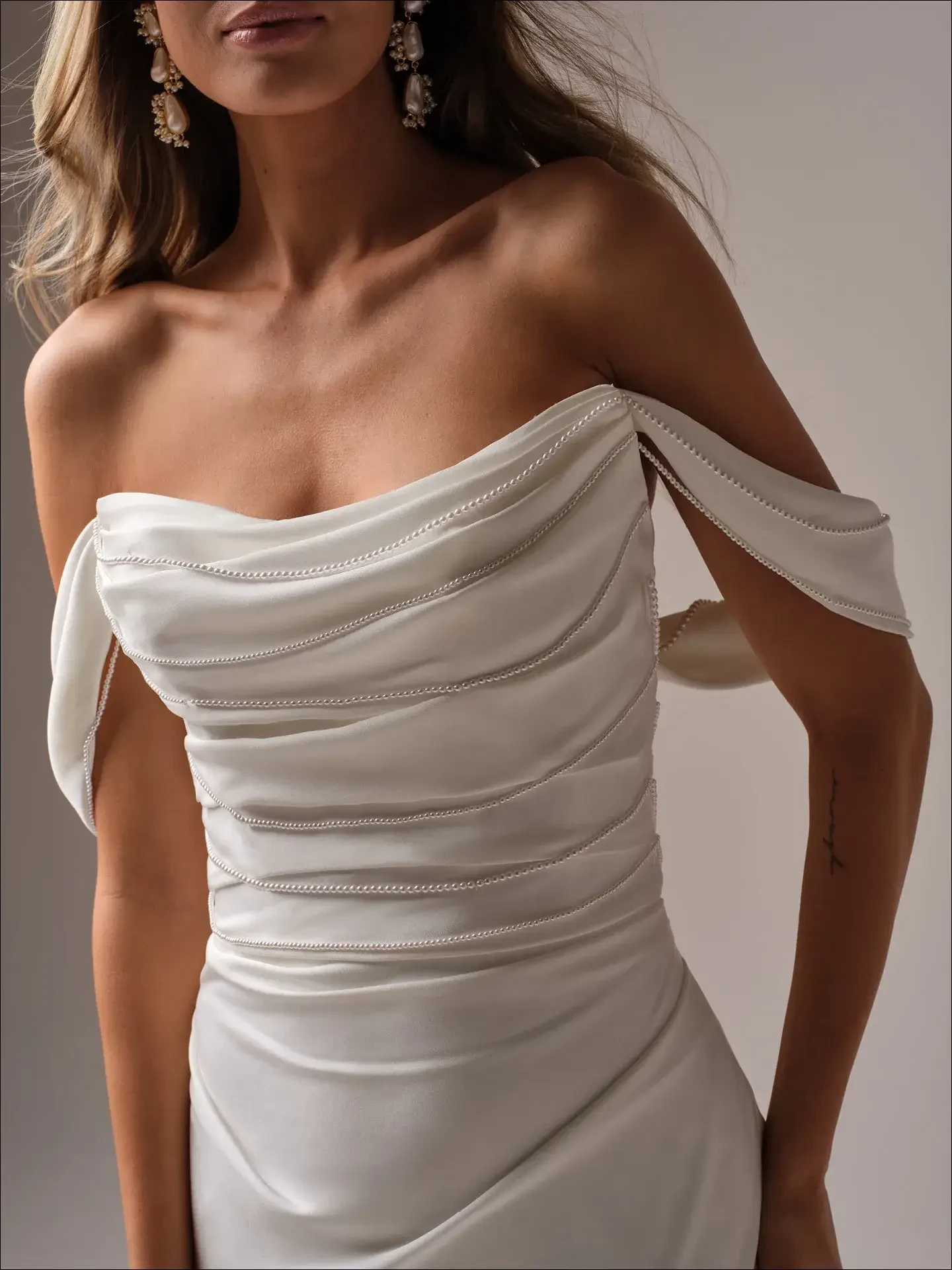 model is wearing a romantic off the shoulder fit and flare wedding dress