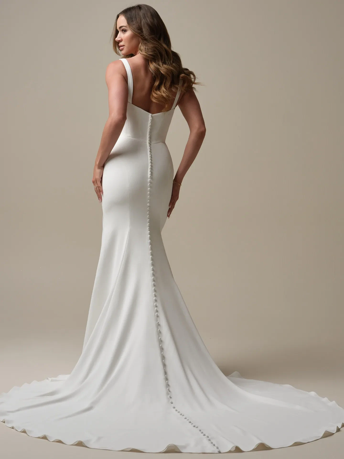 model is wearing a long sleeve crepe fit and flare wedding gown