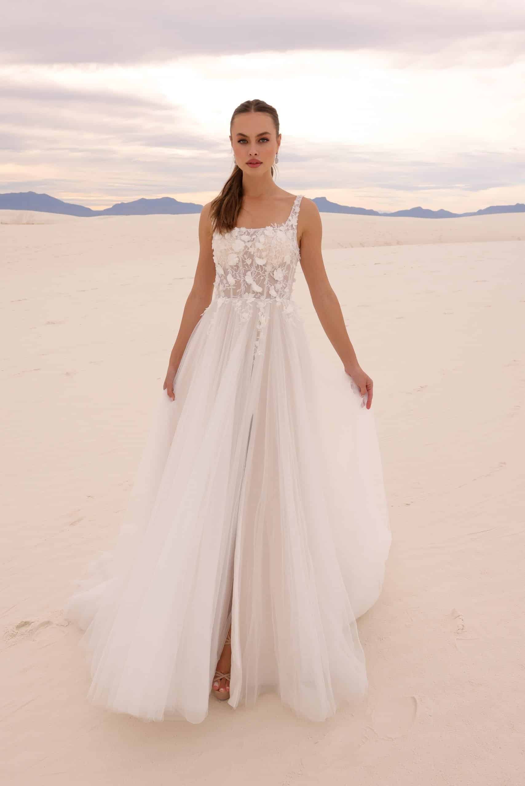 Woman standing in the sand wearing a flowy wedding dress