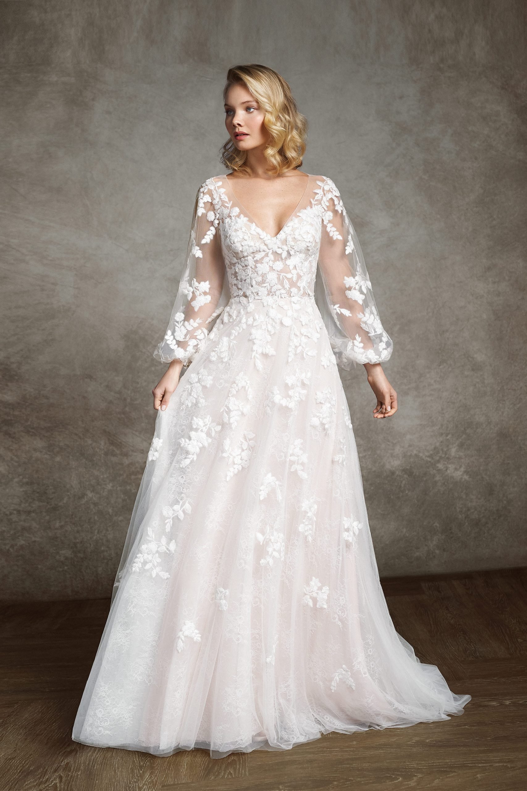 Blonde haired bride standing with lace long sleeve gown