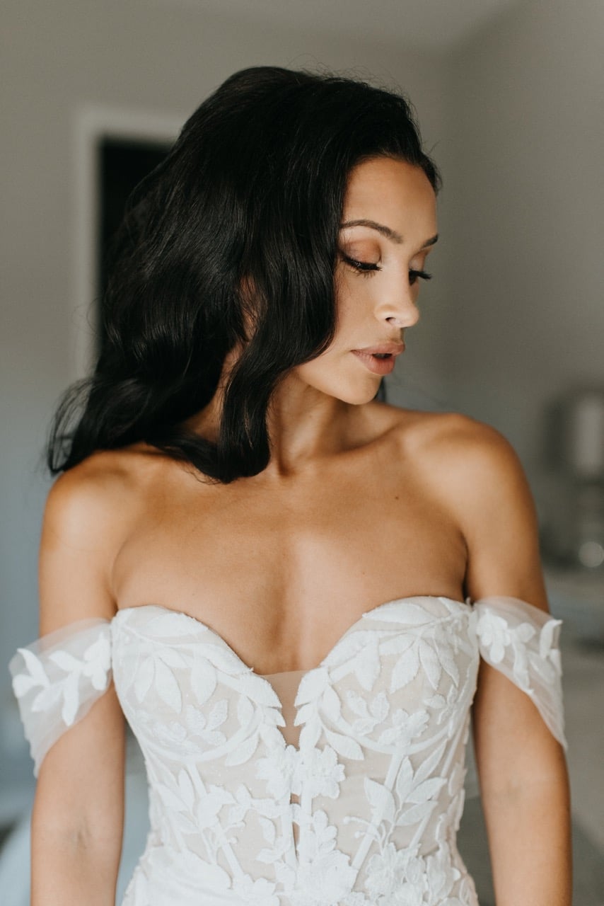 Bride with dark long hair looking off to the side wearing off-the-shoulder-gown